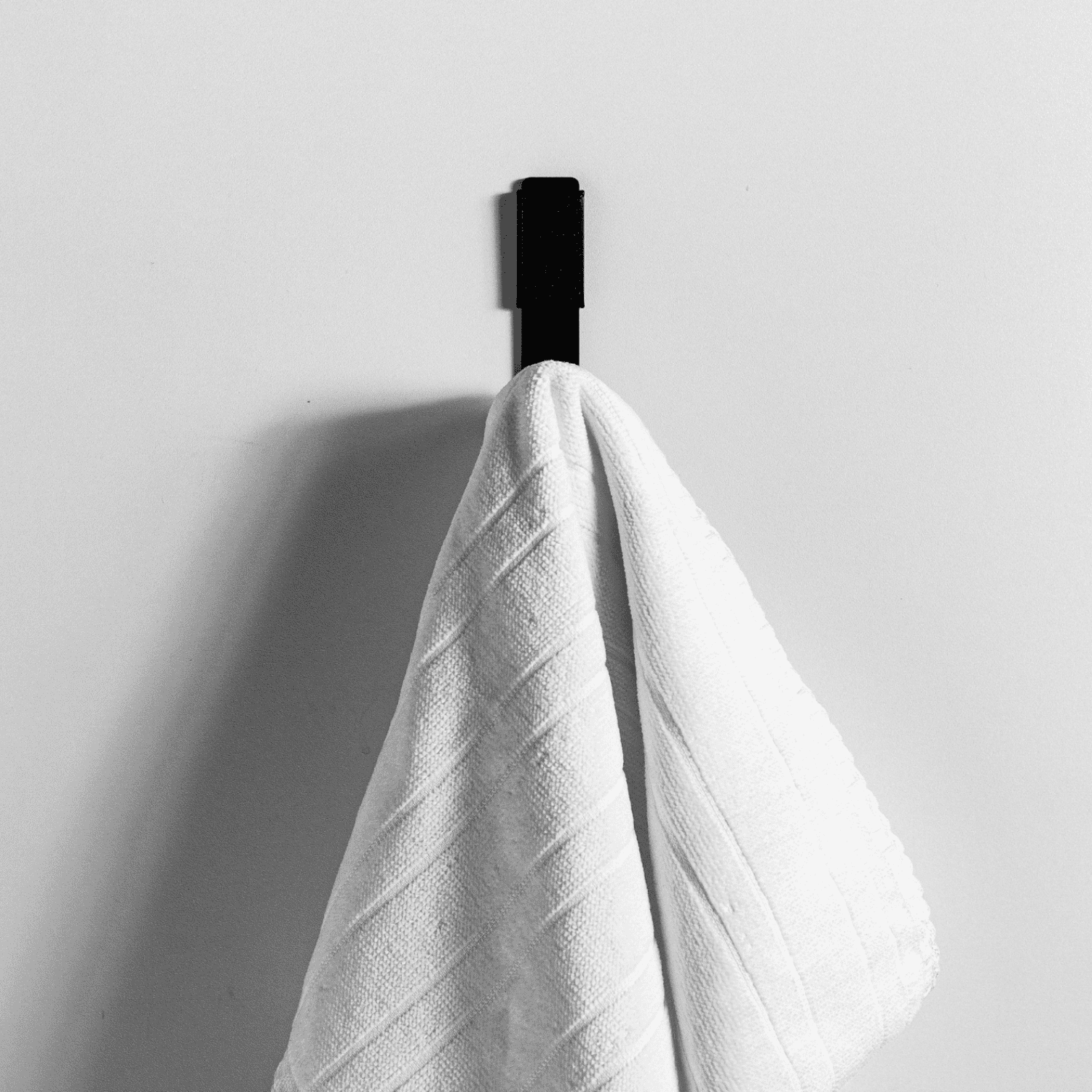 gancho de parede preto com toalha